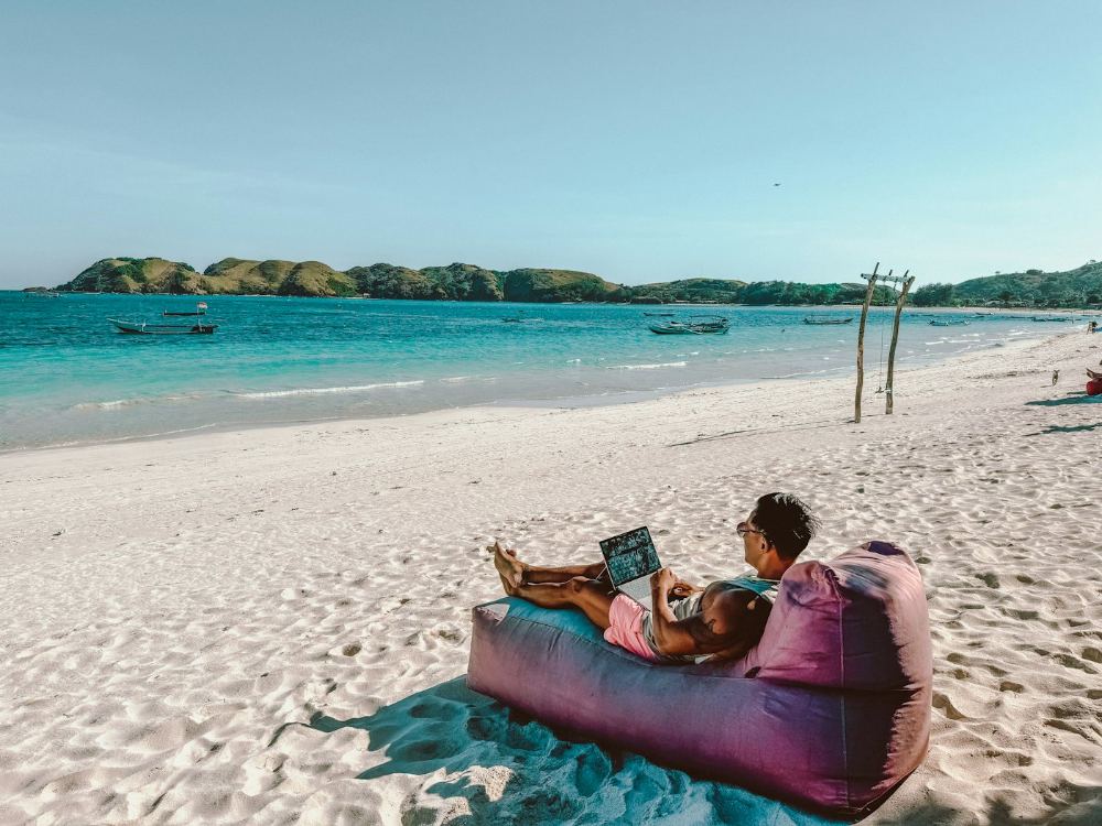 Digital nomad working on a laptop on a beach